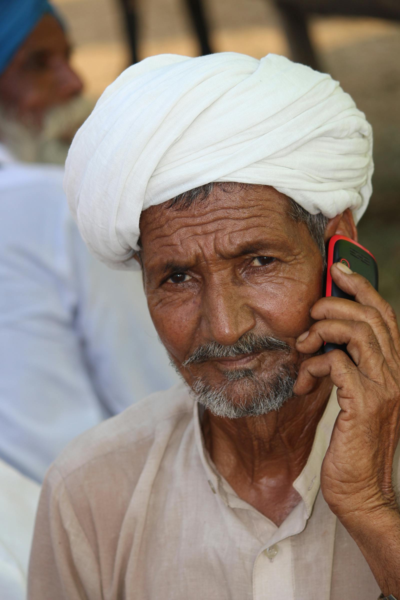 Elderly Indian man in a white turban using a mobile phone
