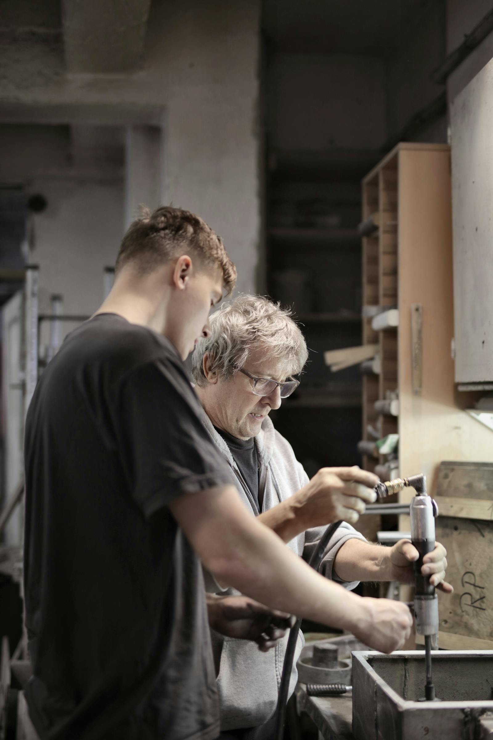Apprentice working alongside a master craftsman in a workshop
